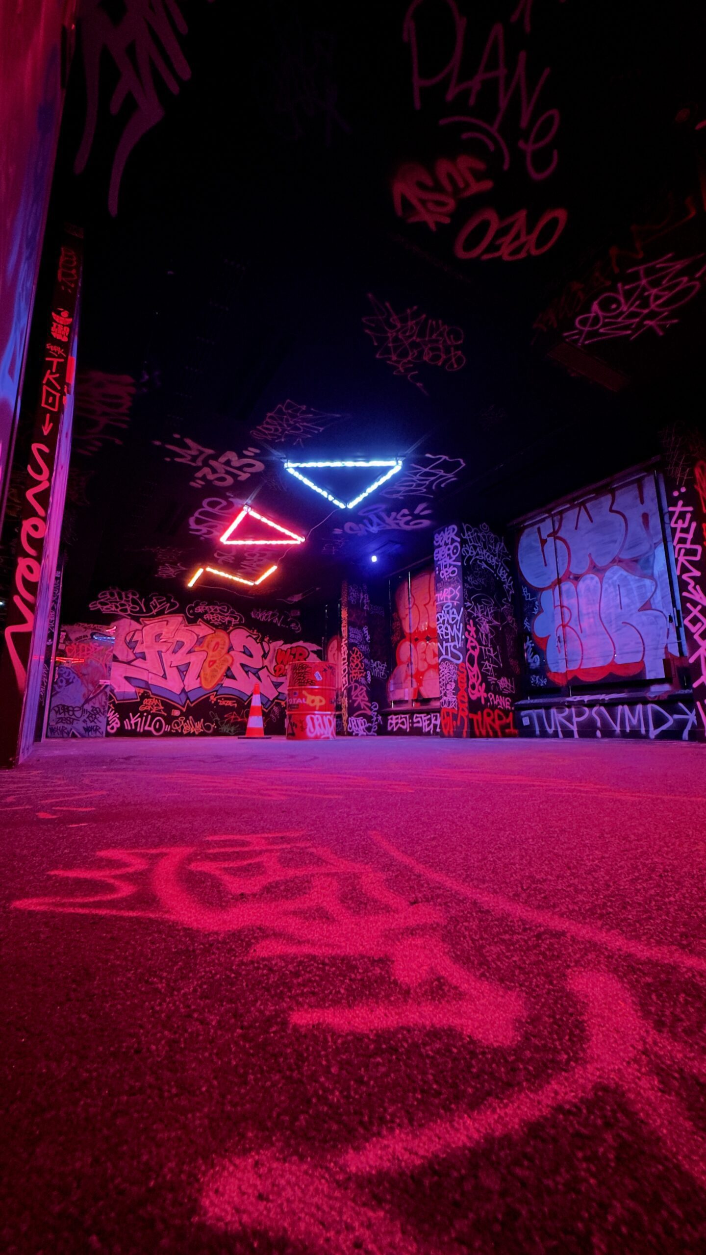 Salle de graffiti aux néons roses et bleus.