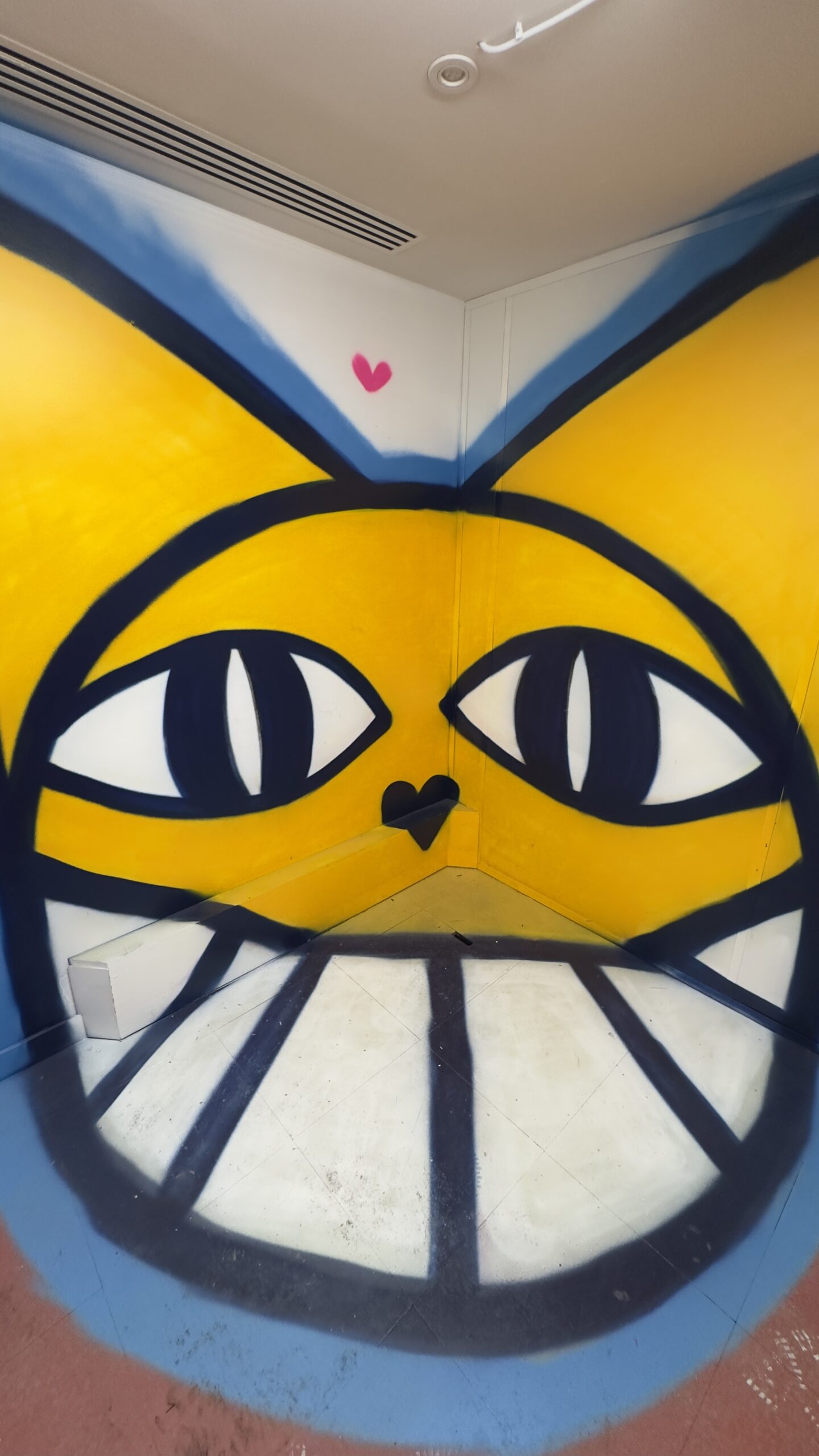Fresque du chat jaune avec grands yeux et sourire.